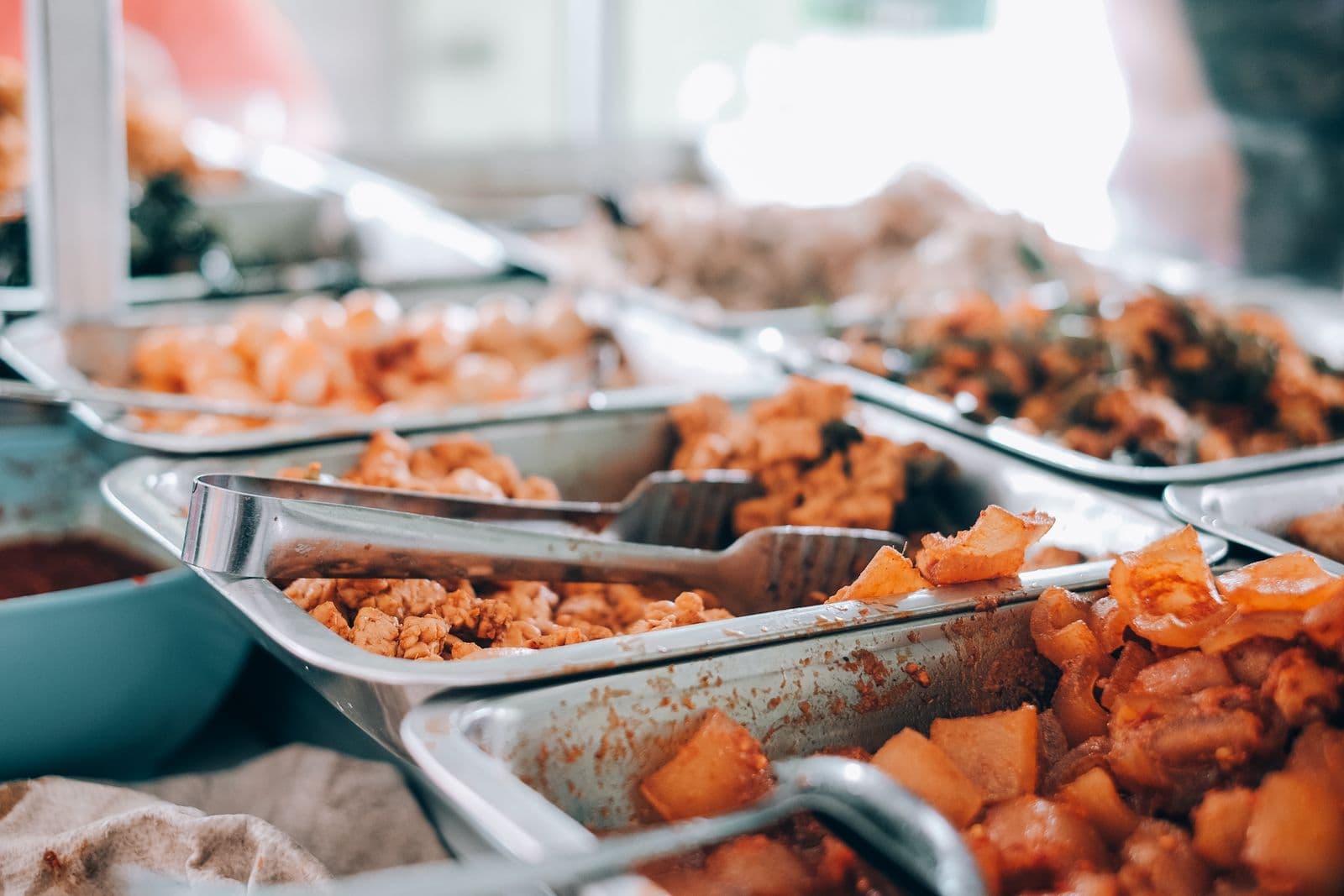 Hot catering trays of food with serving tongs